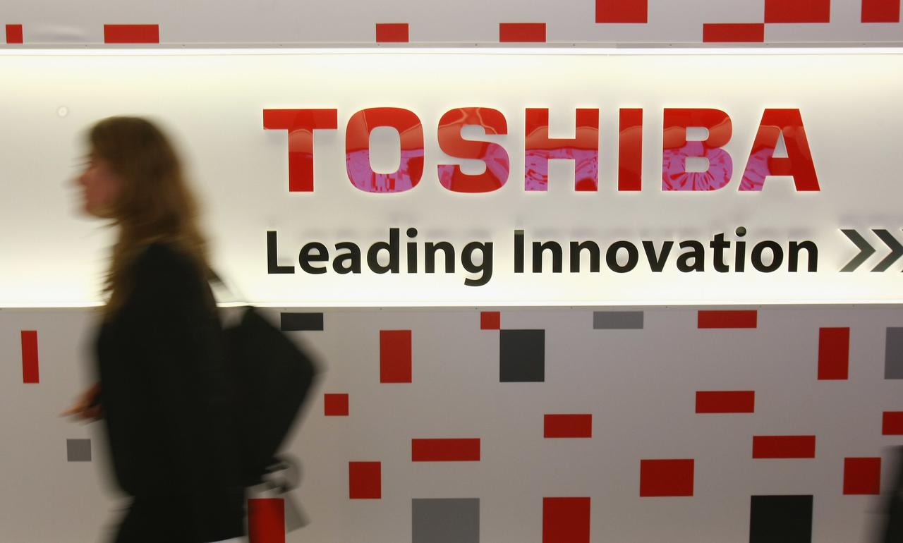 東芝の看板の前を通り過ぎる女性