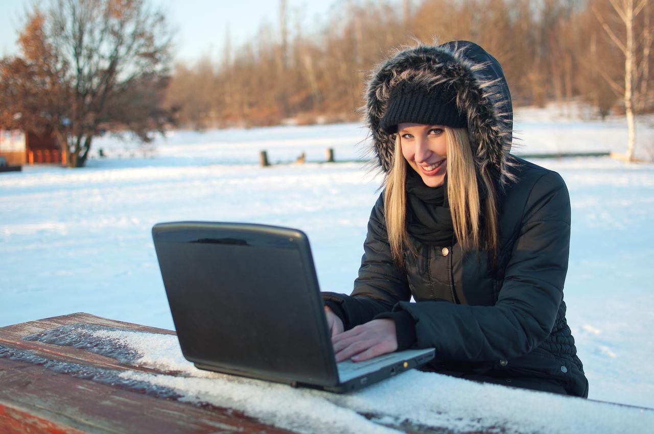 雪景色の中パソコンを使う女性