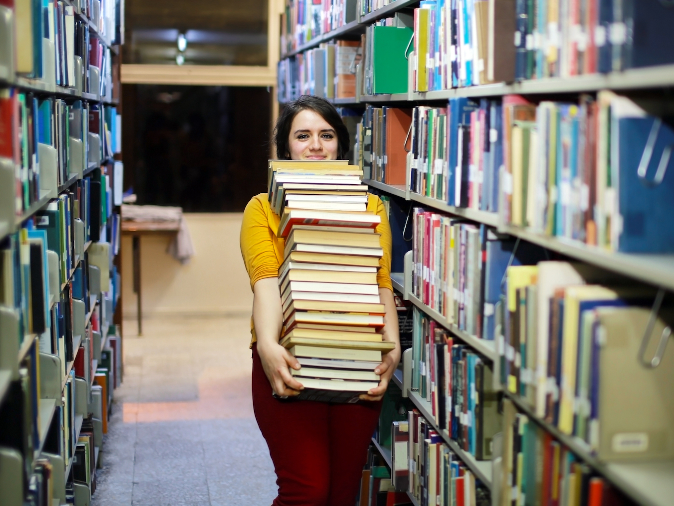 図書館で大量の本を抱える女子学生
