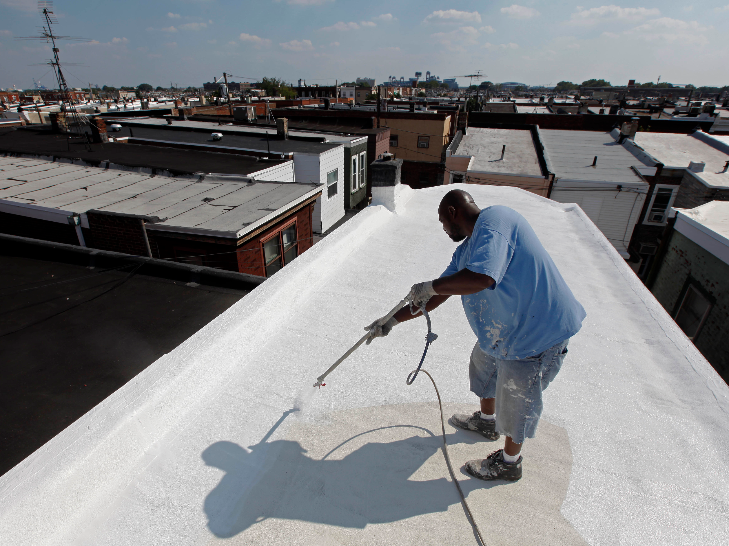 屋根を白く塗装する男性