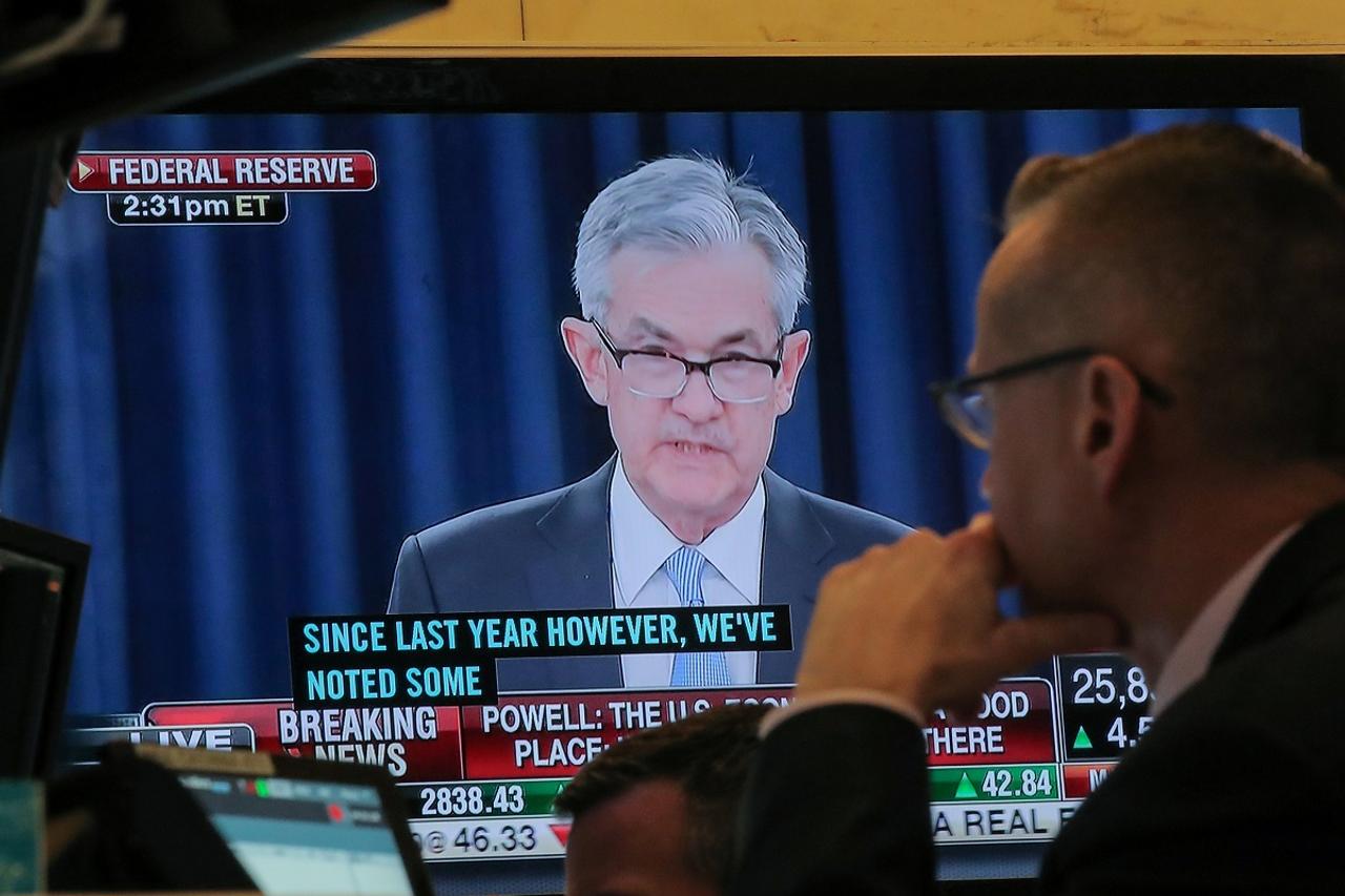 FRBのパウエル議長の記者会見の様子を映す画面を見るニューヨーク証券取引所のトレーダー。