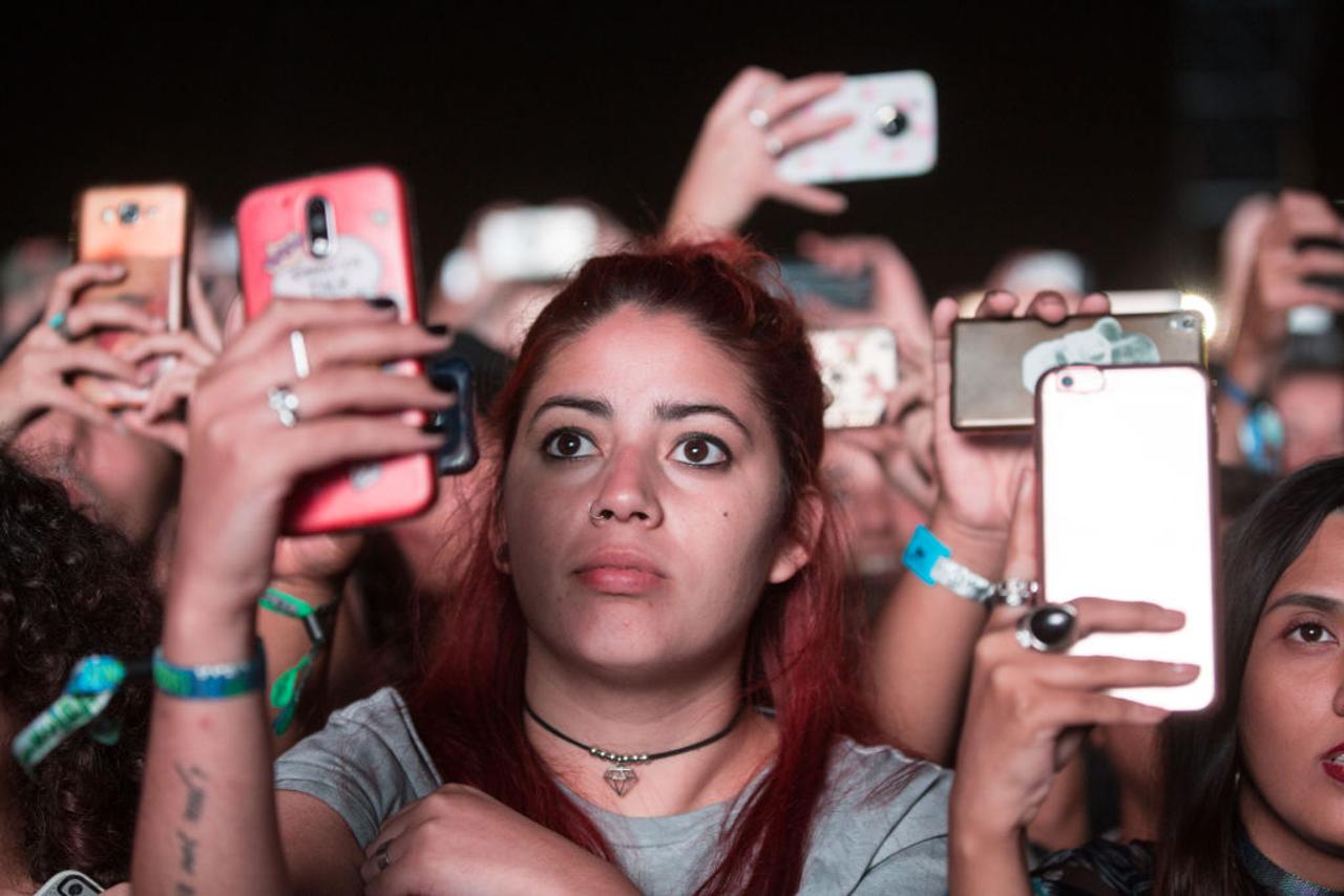 スマートフォンでコンサートの様子を撮影する女性