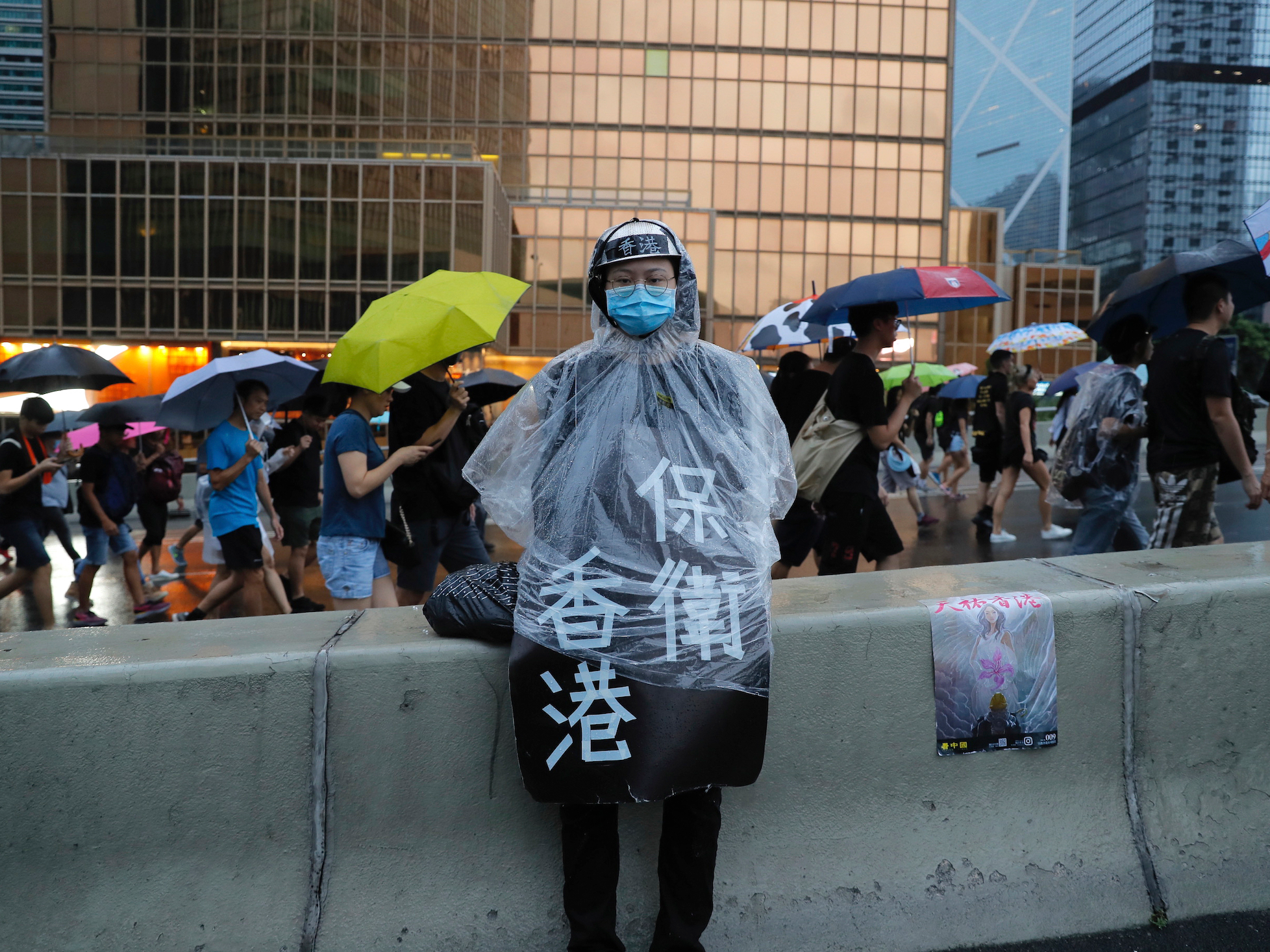 8月18日、香港で行われたデモ行進中、レインコートを着た参加者が｢香港を守れ｣と書かれたプラカードをつけている。