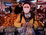 2020年4月3日、北京の食品市場で買い物をしている中国人女性は顔全体を覆うマスクを着用している。