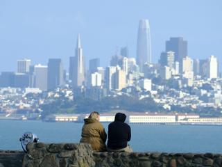 サンフランシスコのスカイラインを望む展望台に座るカップル。