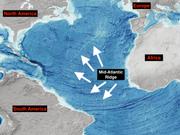 大西洋の海底地形図。白い矢印が大西洋中央海嶺を指している。