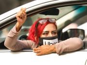 ライドシェアドライバーのテレサ・メルカードさんが拳を上げて訴える。2020年10月8日、配車サービスのギグワーカーが、ロサンゼルス市庁舎前の道路を車で塞ぎ、デモを行った。