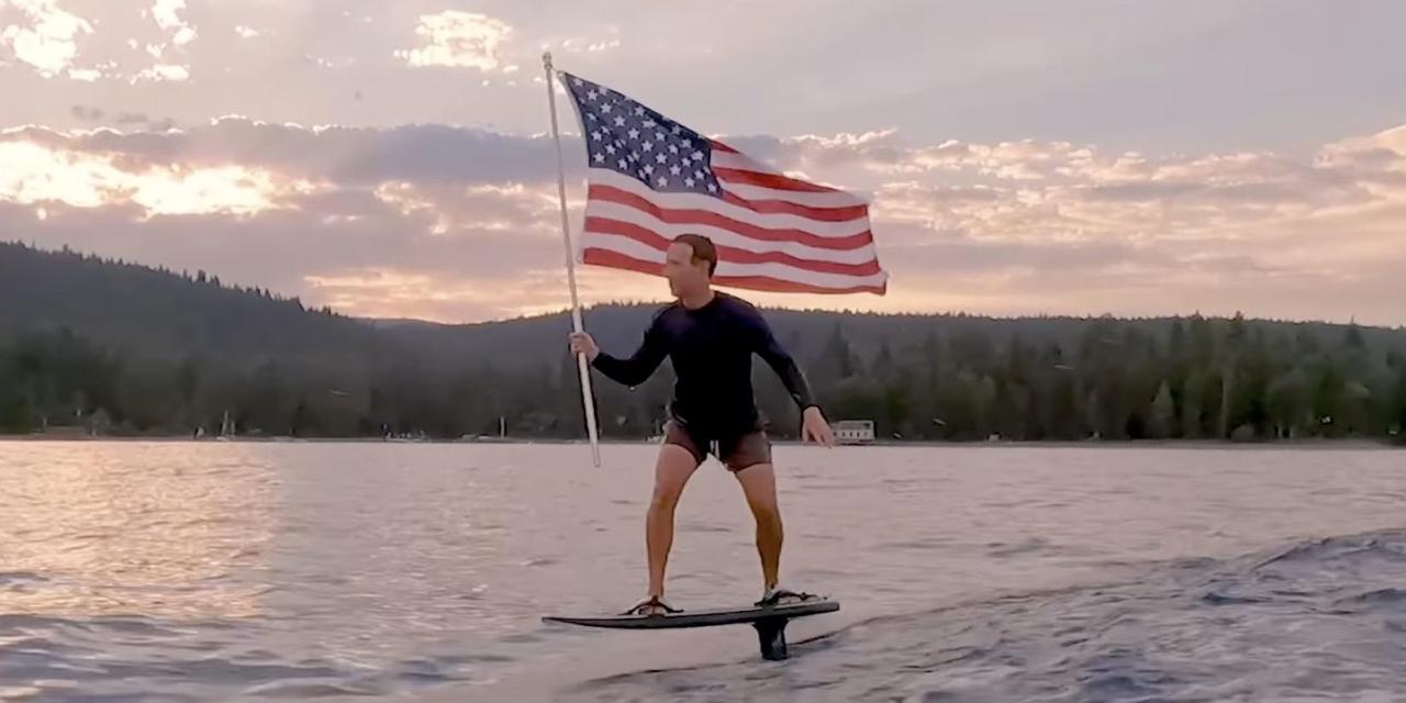アメリカ国旗を手に電動サーフィンをするフェイスブックCEOのマーク・ザッカーバーグ氏。フォーブスの2021年長者番付に載った最年少ビリオネア15人の中で、一番の資産家だ。