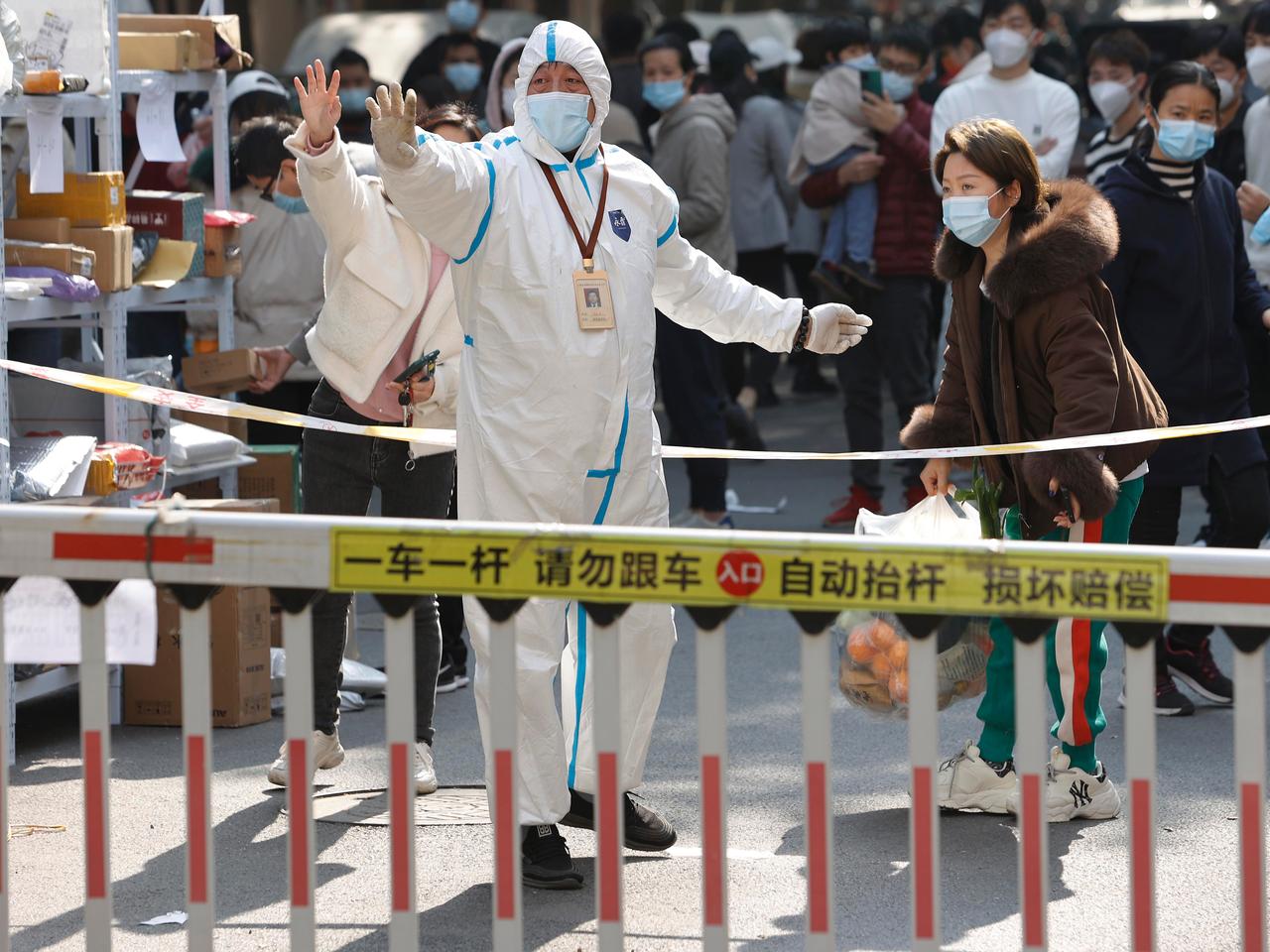 個人用保護具（PPE）を着用したボランティアが、封鎖されている住宅地の入口で食料を配布している。2021年11月26日、中国・上海で。