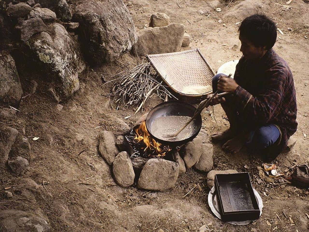 ブータンで焚き火をしながら調理する人