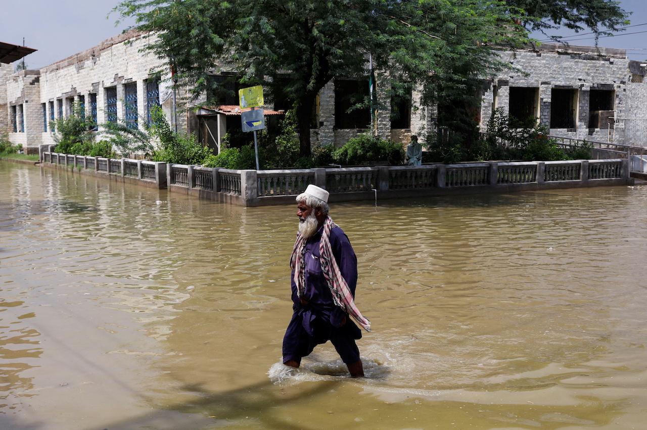 洪水に見舞われた町を歩く男性。2022年8月30日、パキスタンのジャコババードで