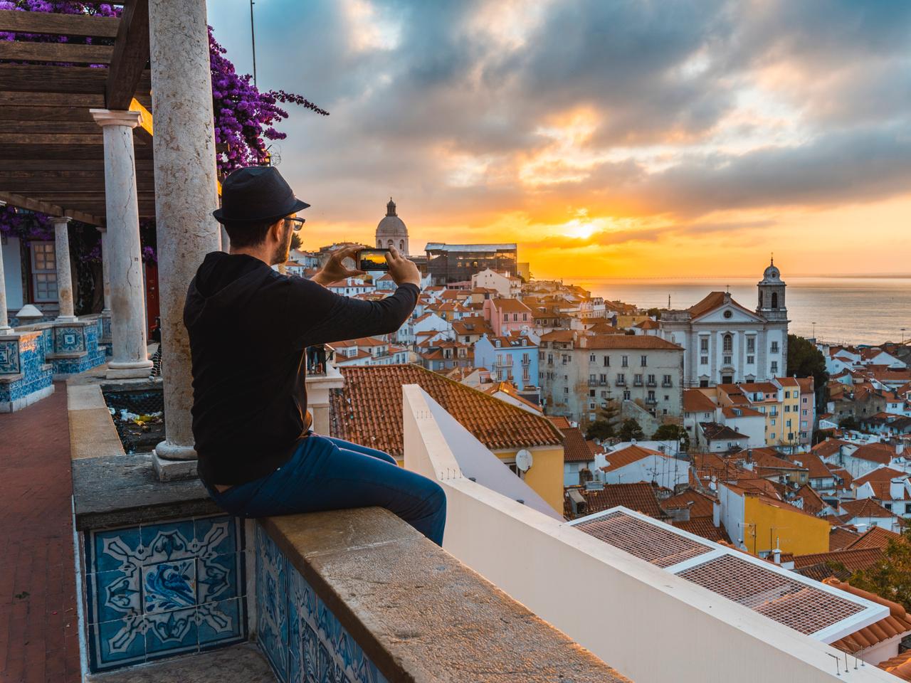リスボンの日の出と写真を撮る旅行者。ポルトガルの首都リスボンは、リモートワーカーに世界一の都市に選ばれた。