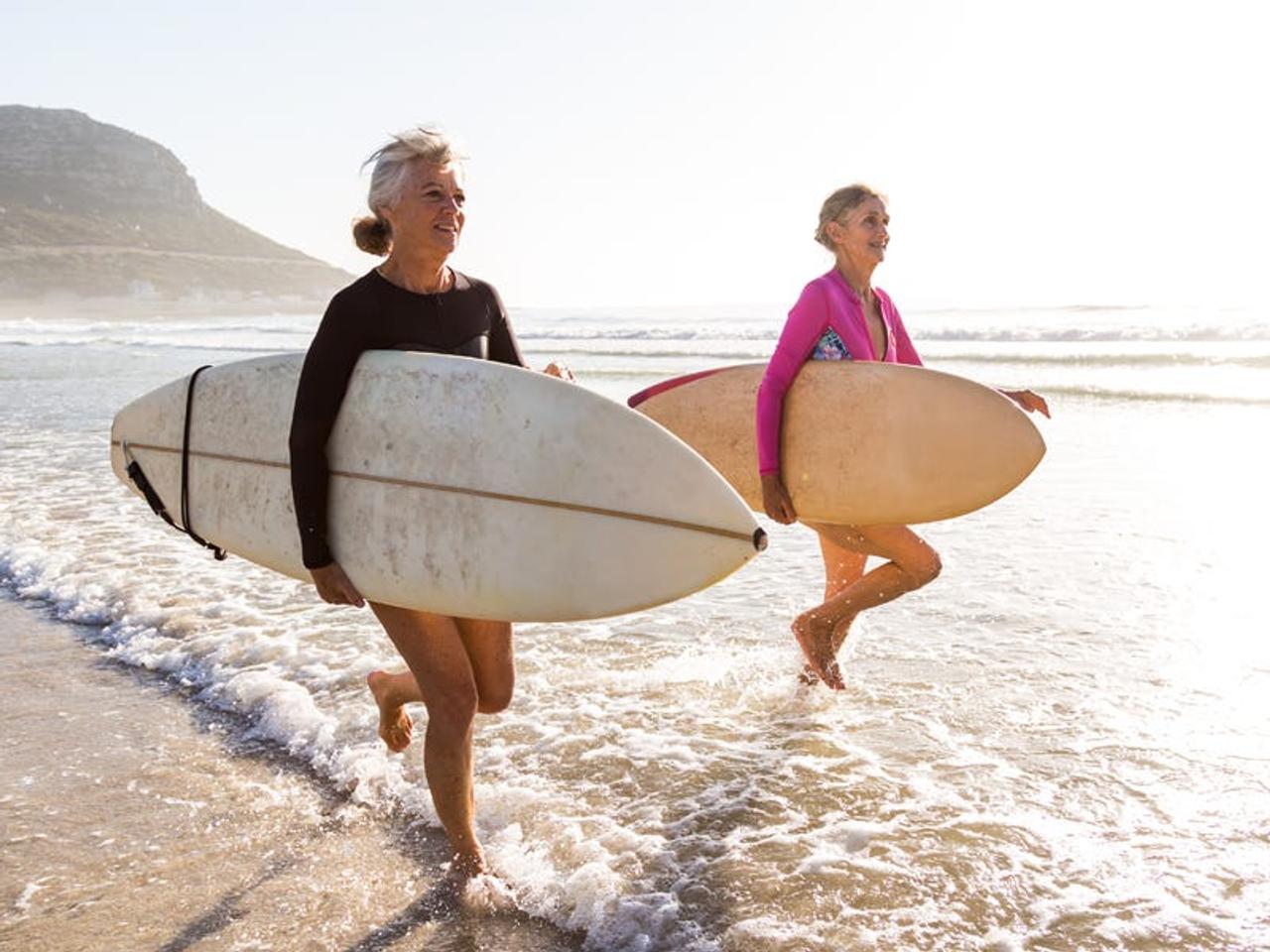 サーフボードを抱え走る年配の女性たち