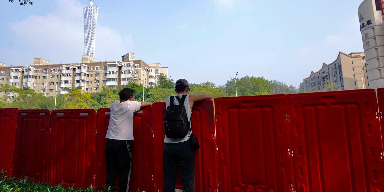2022年11月11日、中国南部の広東省広州市海珠区に張り巡らされたバリアの反対側を眺める住民たち。
