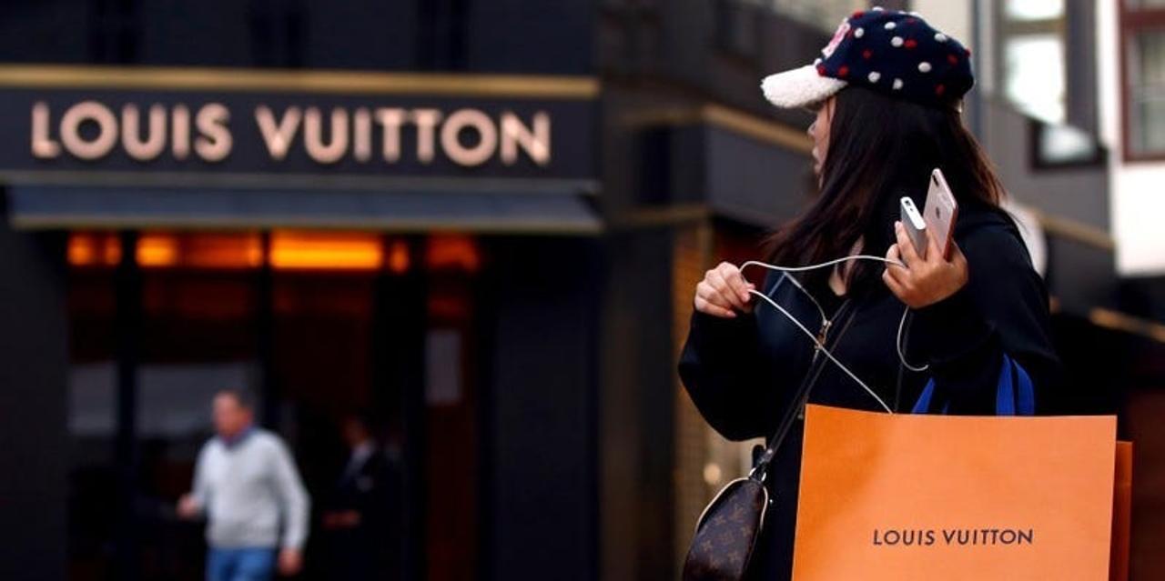 ウィーンのルイ・ヴィトンの店の前でルイ・ヴィトンブランドのショッピングバッグを持った女性。
