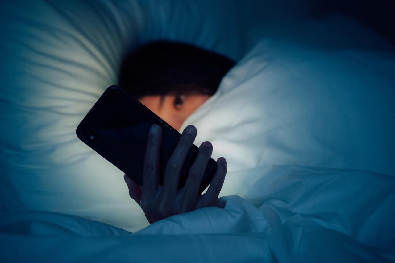ベッドでスマートフォンを使う人