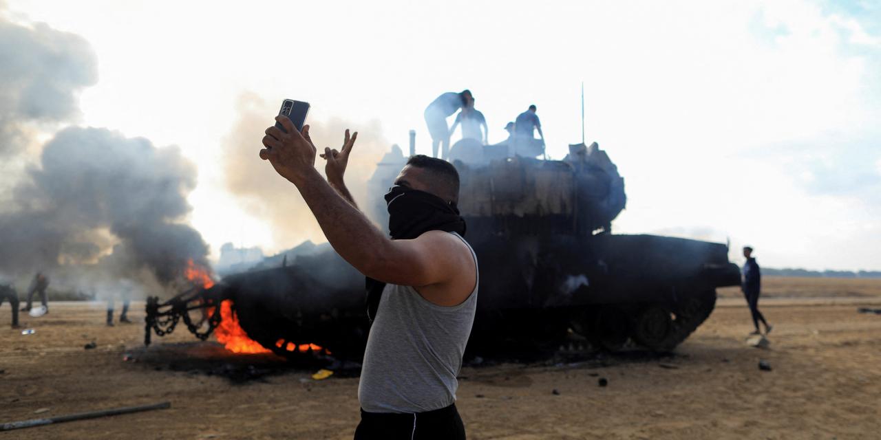 炎上するイスラエル軍車両の前で自撮りするパレスチナ人男性。