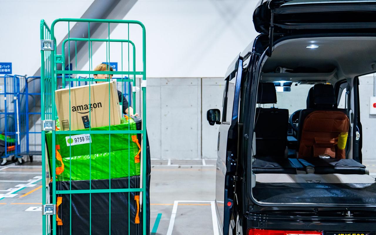 軽乗用車に荷物を運び入れるドライバー