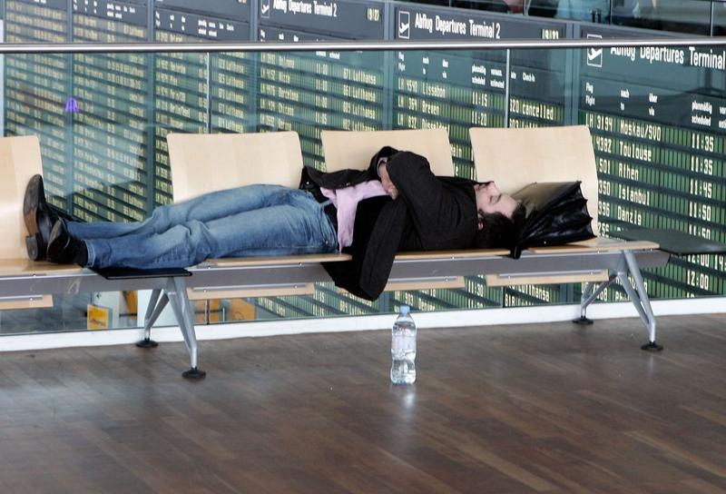 空港のベンチで寝る男性