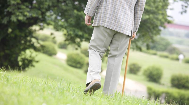 杖をついて歩く男性の後ろ姿