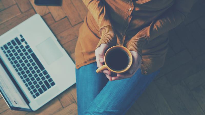 コーヒーを両手で持つ女性
