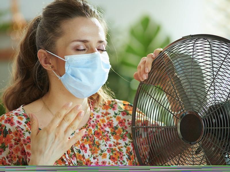 マスクをつけて暑がる女性