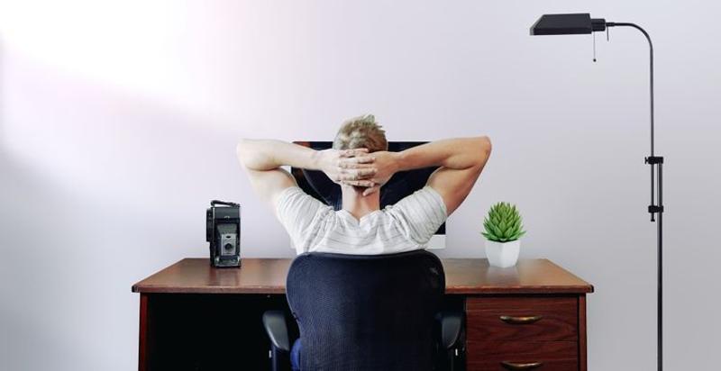 デスクで頭を後手にしている男性