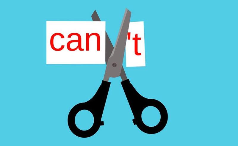 「can't」と書いた紙を切っているハサミ