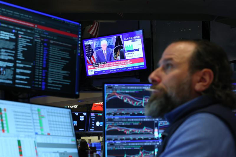 Traders listen to President Donald Trump's speech on the floor of the New York Stock Exchange.