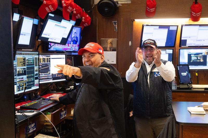 Two traders at the NYSE wearing Trump hats and cheering