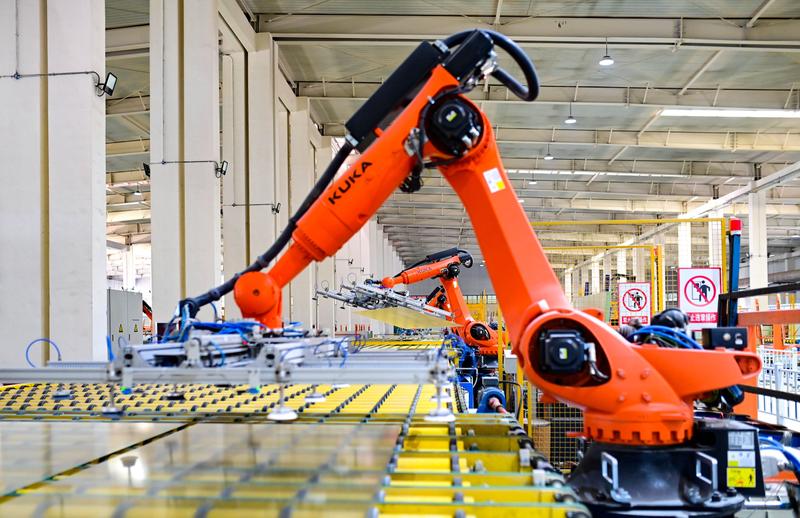Robotic arms work on an intelligent production line of photovoltaic glass at a factory