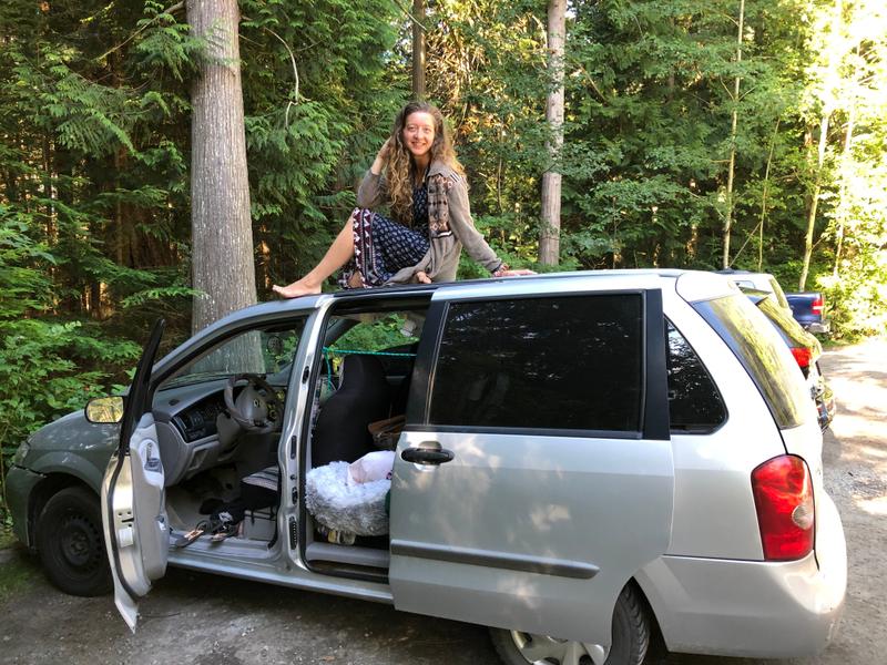Woman sitting on top of car, smiling