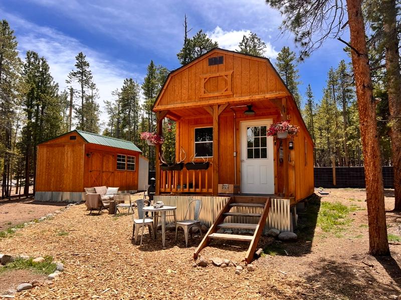 A wood tiny house with seating in front of it.