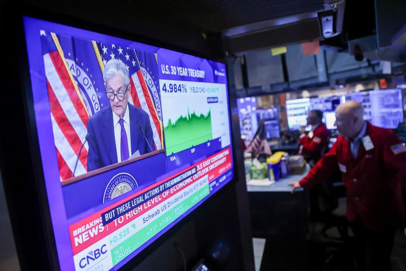 A television station broadcasts Jerome Powell while traders work on the floor of the New York Stock Exchange
