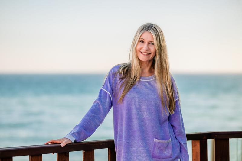 A woman stands in front of the ocean.