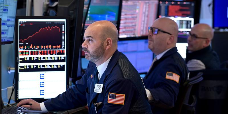 A line of traders looking up at a monitor at the NYSE