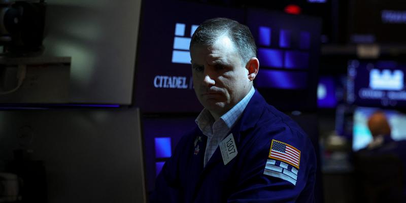 Trader at the New York Stock Exchange looking at a monitor in the dark