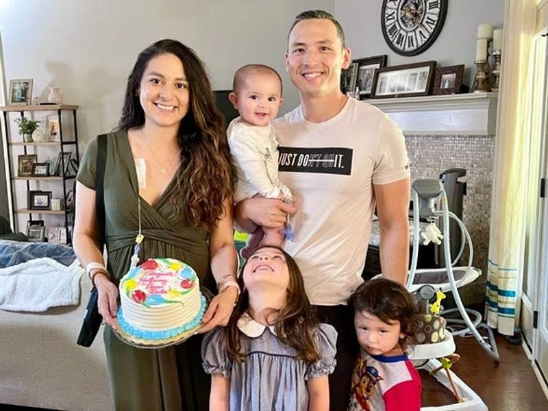 a family of five holding a birthday cake in their home.
