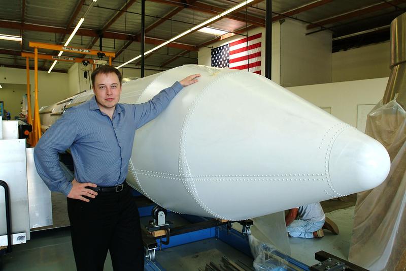 Elon Musk puts his left hand on the top of a rocket. It's SpaceX's first rocket model, called the Falcon 1.