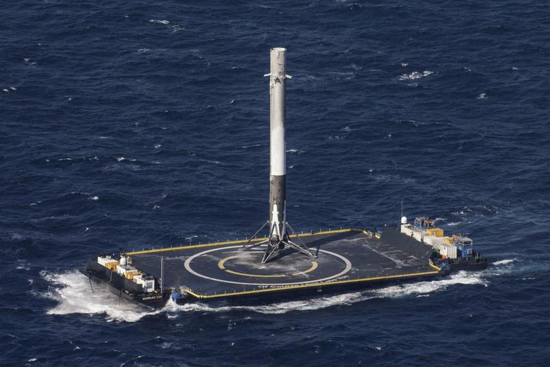 A SpaceX rocket lands on an ocean-based pad.