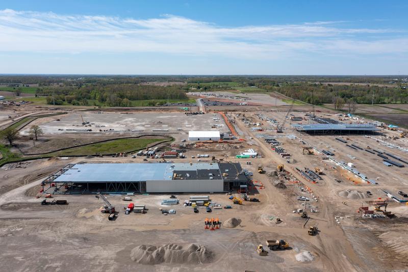 a massive building under construction, surrounded by dirt