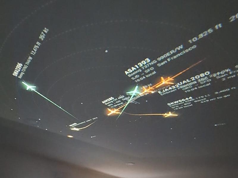 Air traffic radar display shows multiple aircraft icons and flight paths with flight identification labels.