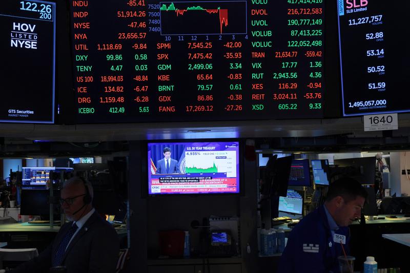 A television displays Kevin Warsh, chairman of the Federal Reserve, during a press conference as traders work on the floor of the New York Stock Exchange