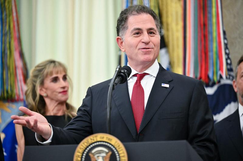 Michael Dell speaking at the White House with his wife photographed in the background