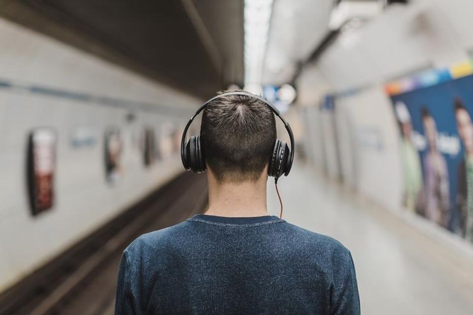 駅のホームでヘッドホンをする男性の後ろ姿