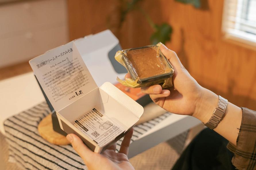「黒胡椒クリームチーズのみそ漬」を箱から取り出す編集部員