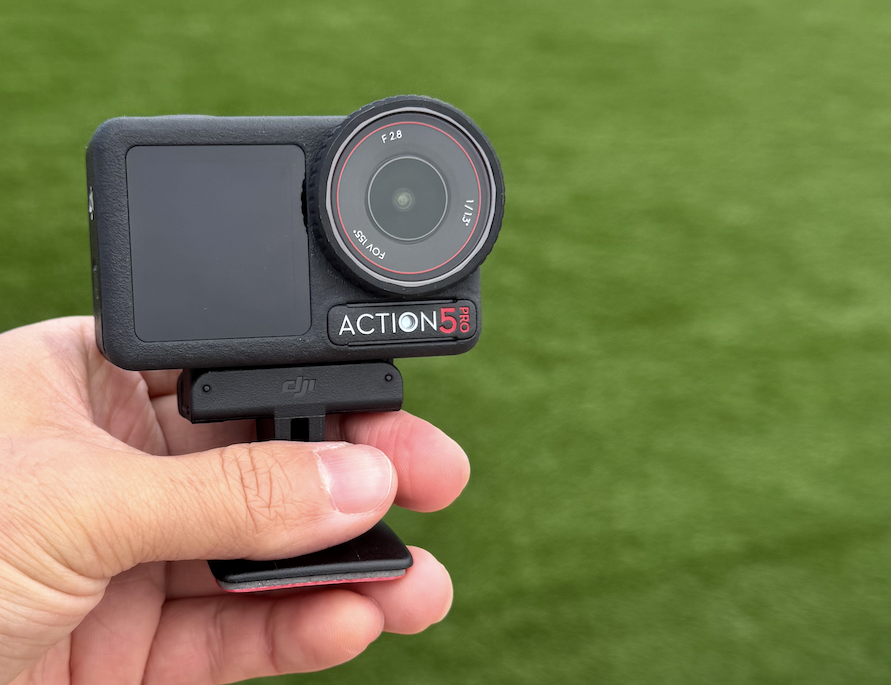 人口芝の前でDJIアクション5プロを手に持つ