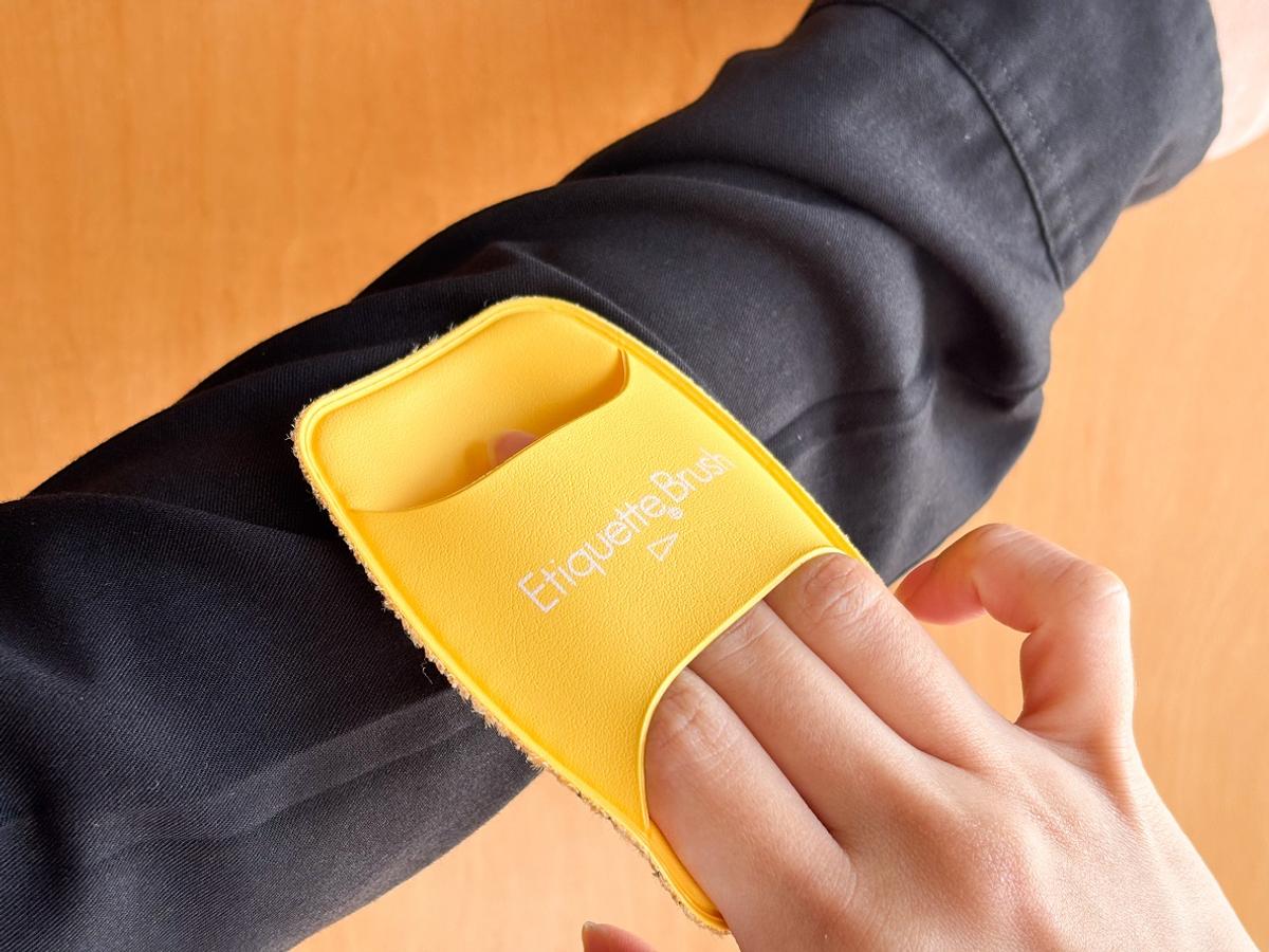 にエチケットブラシで黒いシャツをブラッシングしている様子