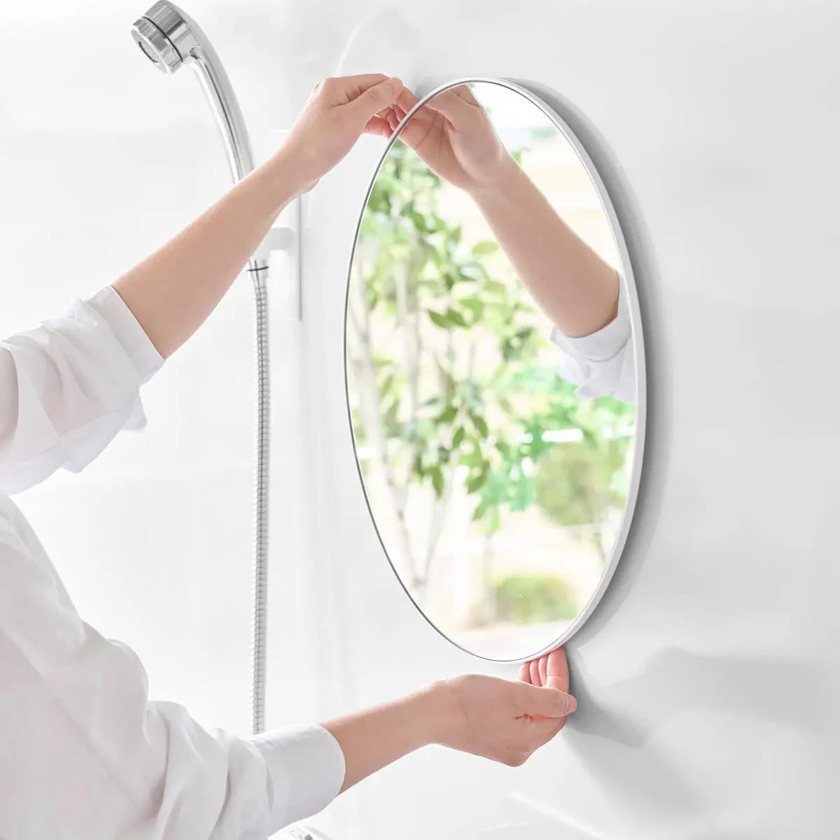 山崎実業「マグネットバスルームミラー タワー 丸型 42cm」を取り外そうとする様子