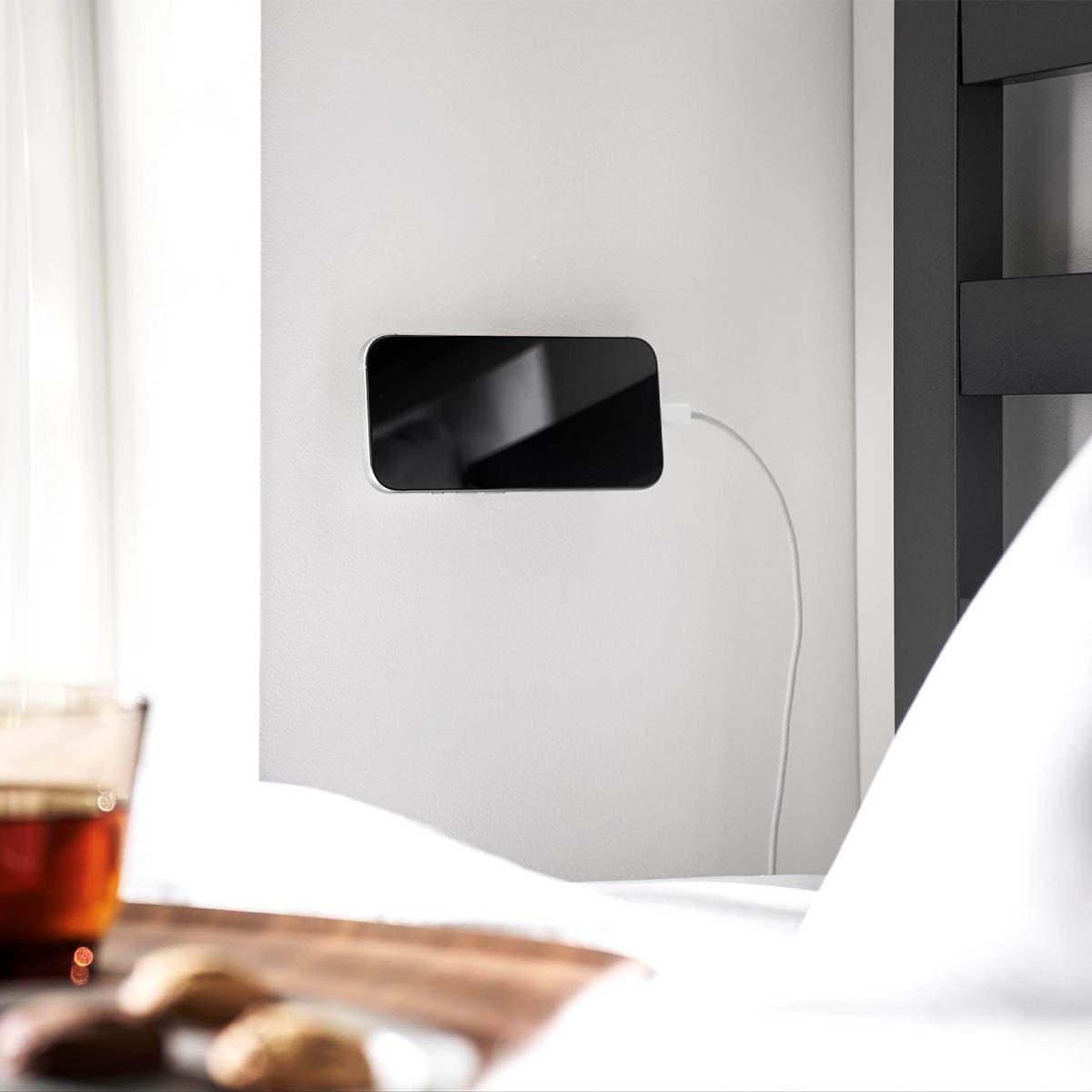 山崎実業の「角度が調節できる壁付けスマホホルダー タワー」をベッドサイドの壁につけて充電しているところ